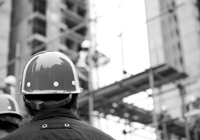 Carpenter in front of building Carpenter in front of construction site building in Pilbara